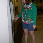 Young woman uses an atm in an ugly Christmas sweater