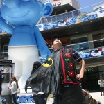 Photo: Guy wearing poinsettia vest and Batman cape in front of Smurf blowup in Santa Monica mall