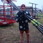 Photo of man in ugly Christmas sweater holding rowing oars