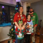 Ugly Christmas sweater family portrait in front of a Christmas tree